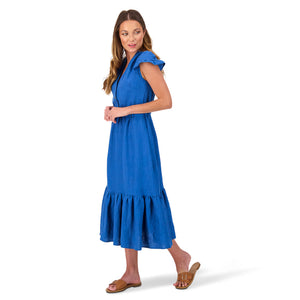 A model is wearing the sustainable quinn midi-dress in blue deadstock linen. She is facing front and to the right, with her left foot a step behind her and her arms folded in front.